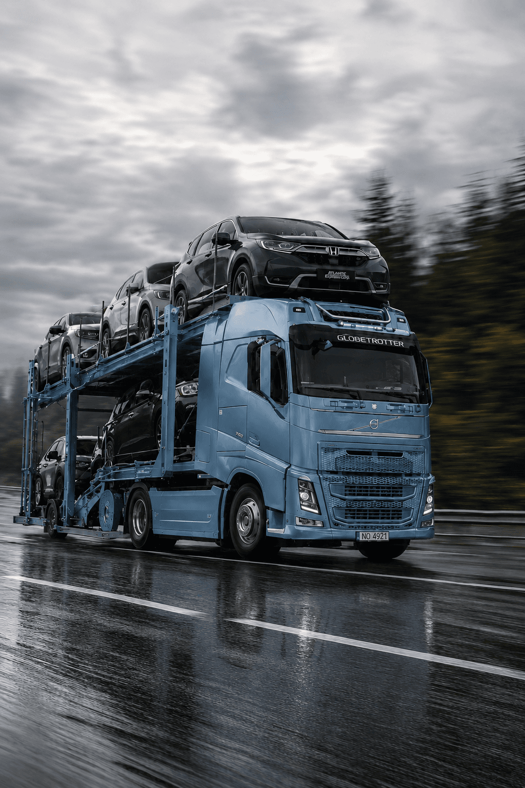 Автовоз Volvo FH із легковими авто на мокрій трасі